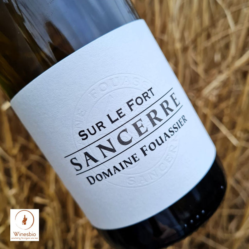 Wine bottle labeled 'Sur Le Fort Sancerre Domaine Fouassier' on a bed of straw.